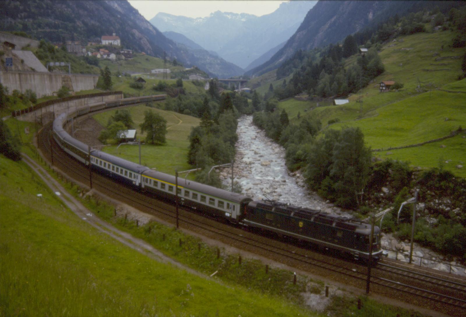 Treno passeggeri trainato da una Re 66 in livrea verde, in linea nei pressi di Wassen il 30.06.1985.jpg